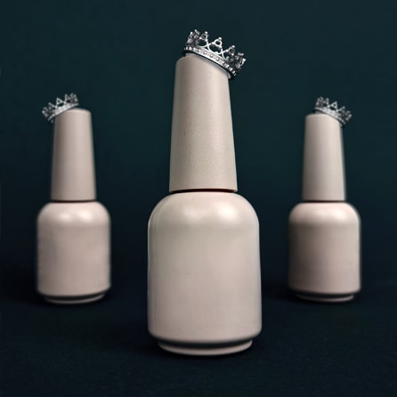 Three pink gel polish bottles with crowns on top of each bottle