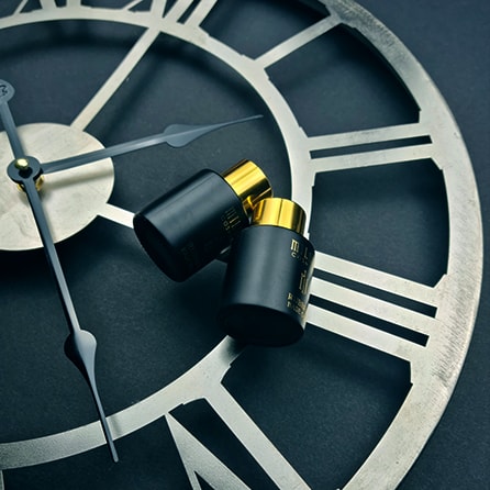 Two black bottles with golden caps lying on the clock